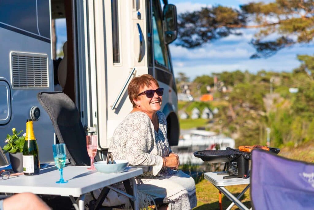 Gäst som sitter och ler i solen utanför husbilen på City Strömstad