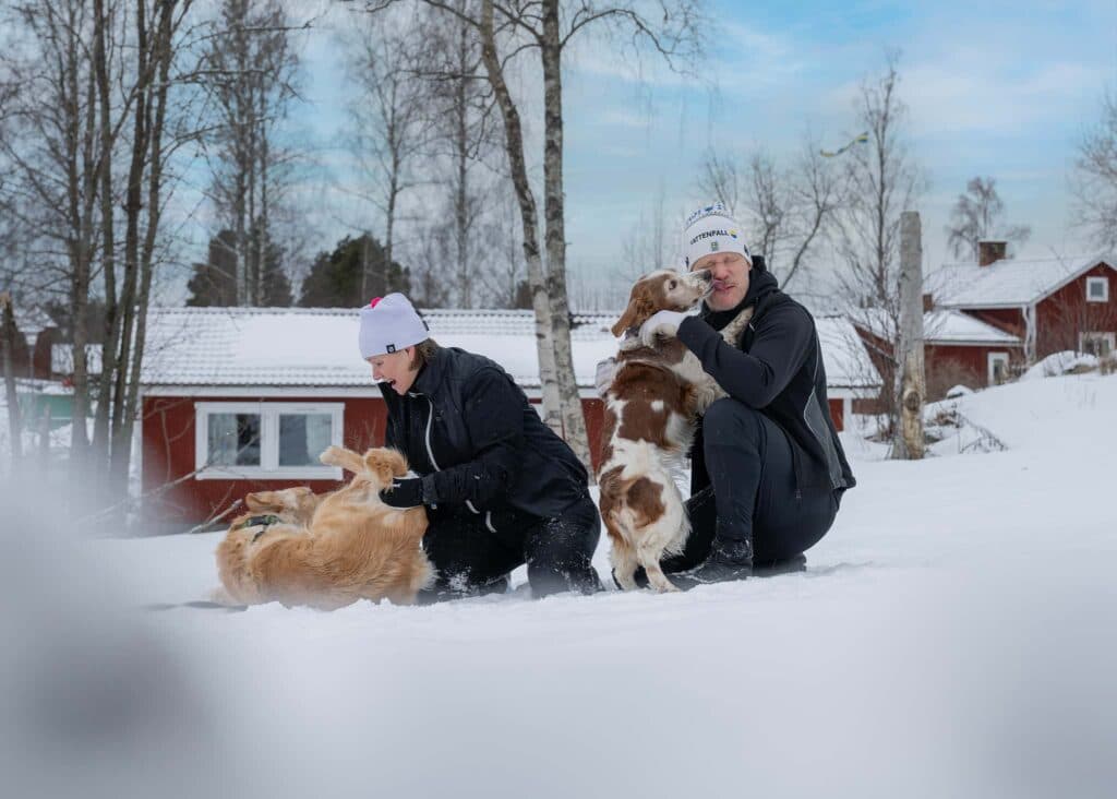 Person med hund utanför en snötäckt stuga på First Camp Lugnet Falun