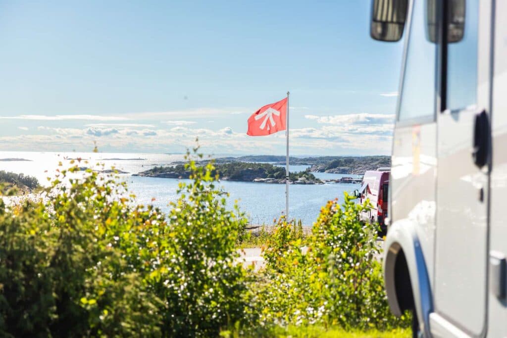 Husbil framför havet och First Camp flagga på City Strömstad