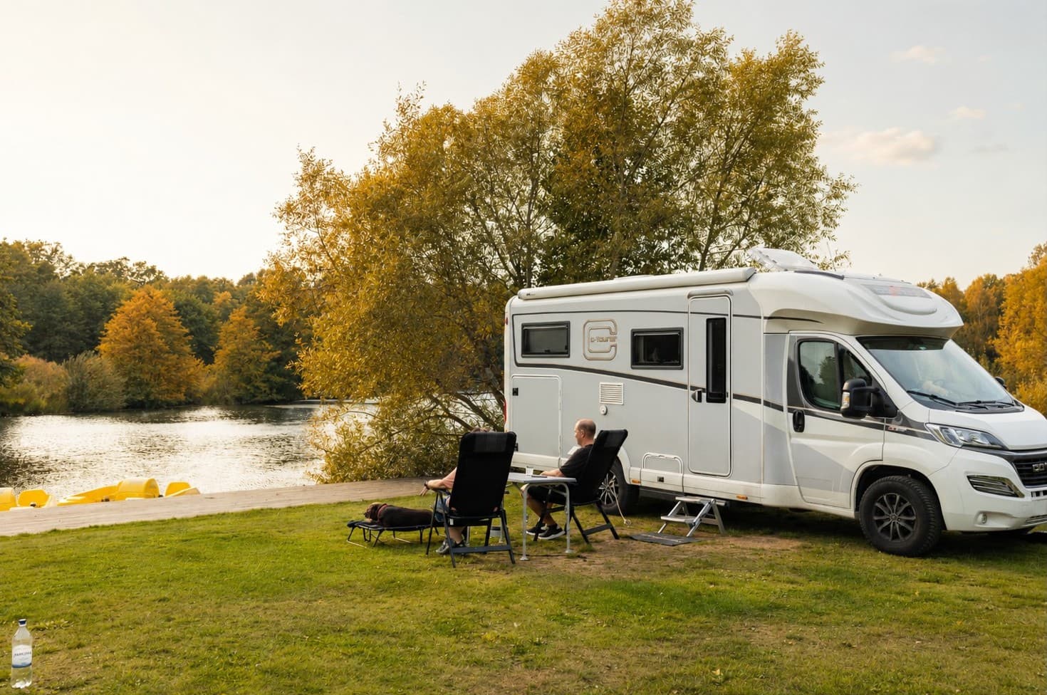 höstcamping med vacker natur och husbil och människor som sitter och titar ut över vattnet